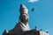 Antique egyptian sphinx sculpture from gray granite against blue sky with flying pigeon