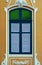 Antique, elegant arched window with louvered shutters and green glass.