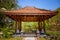 Antique gazebo pavilion with a roof asian style pagoda. In a summer tropical garden. A stone path along which the statues stand