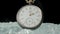 Antique grey pocket watch among shiny crystals or sparkling glass splinters. Round retro clock with a white dial, hands