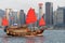 Antique junk boat with tourists in Victoria Harbour, Hong Kong, skyline of buildings in background