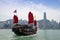 Antique junk boat with tourists in Victoria Harbour, Hong Kong, skyline of buildings Central and white clouds and blue sky in back