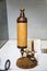 Antique Leeuwenhoek microscope in light brown on a white table, Microbiology