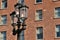 Antique luminous triple street lantern against the house with brick wall