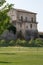 Antique medieval wall with climbing plants and house in Italy street