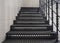 Antique metal staircase with black richly decorated wrought-iron steps and railings