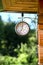 Antique outdoor clock hanging outside a wooden house made of logs