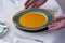 Antique plate filled with carrot soup being served on elegant table set with beautiful antique silverware