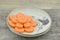 Antique plate with slices carrot on wooden