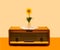 An antique radio with lovely sunflower in the middle in transparent glass vase on it. Minimal retro arrangement against beige and