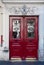 Antique red door with framed wooden panels and ornate grids on door windows of old building in Paris France. Vintage doorway