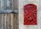 Antique red mailbox and rustic wooden door. Letters are no longer written