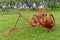 Antique red plow with wheels in nature