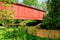 Antique Red Wood Covered Bridge over a River Creek