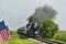 A Antique Restored Steam Engine Approaching Head on Passing a Row of American Flags