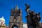 Antique sculpture of Ivo of Kermartin and tower of the medieval gothic Charles Bridge in Prague