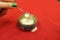 An antique silver and enamel salt shaker stands on a spilled salt on a red cloth background.