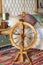 An antique spinning wheel stands on a homespun carpet at the head of the bed