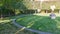 Antique statue on a green lawn surrounded by trimmed trees