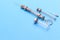 Antique syringe and a glass ampoule next to it on blue background. next to the parts from the syringe