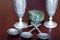 Antique tin cast wine glasses, antique metal soup spoons and a round box of green stone serpentine on a brown wooden background