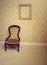 Antique upholstered chair in a wallpapered room