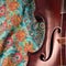 Antique violin closeup, square, against intricate pattern