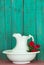 Antique water pitcher and basin with red flowers by rustic green wood background