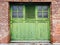 Antique Watervliet Shaker green bifold garage door in brick wall