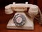 Antique white rotary telephone on a wooden desk.