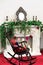 Antique white vintage retro fireplace. Black rocking chair with teddy bear. Mirror,candlesticks. Decoration with spruce branches,