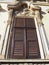 Antique window with shutters. An ornate stucco window in a stone house. Wooden frame, Venetian - brown shutters or