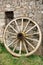 Antique Wood Wagon Wheel against Old Stone Wall