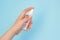 Antiseptic against bacteria spray in woman hand on a blue background. Protective antibacterial spray for hands antiseptic in hand