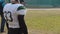 Anxious American football player waiting substitution on field, watching match