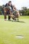 Anxious anticipation of the perfect putt. Two men anxiously watching a golf ball rolling towards the hole on the green.