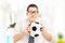 Anxious young sports fan watching football match and holding ball