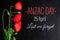 Anzac day. Greeting card with the inscription and poppy flowers on a black background. Flat lay, top view