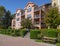 Apartement building on sunny day with bench and paved walkway in front