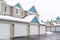 Apartment building exterior with white garages and pitched roofs against sky