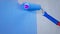 Apartment interior and renovation, closeup paint roller with blue paint moves on white wall in slow motion