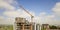 Apartment or office tall building under construction. Brick walls, glass windows, scaffolding and concrete support pillars. Tower