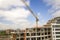 Apartment or office tall building under construction. Brick walls, glass windows, scaffolding and concrete support pillars. Tower