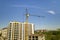 Apartment or office tall building under construction. Working builders and tower cranes on bright blue sky copy space background