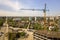 Apartment or office tall building under construction. Working builders and tower cranes on bright blue sky copy space background