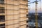 Apartment or office tall unfinished building under construction. Brick wall in scaffolding, shiny windows and tower crane on urban