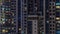 Apartment windows of a glazed skyscraper glow at night with city lights reflection aerial timelapse.