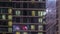 Apartment windows of a glazed skyscraper glow at night with city lights reflection aerial timelapse.