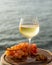 Aperitif cold white wine served in glasses with pink grapes on outdoor tessace witn sea view