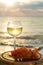 Aperitif cold white wine served in glasses with pink grapes on outdoor tessace witn sea view